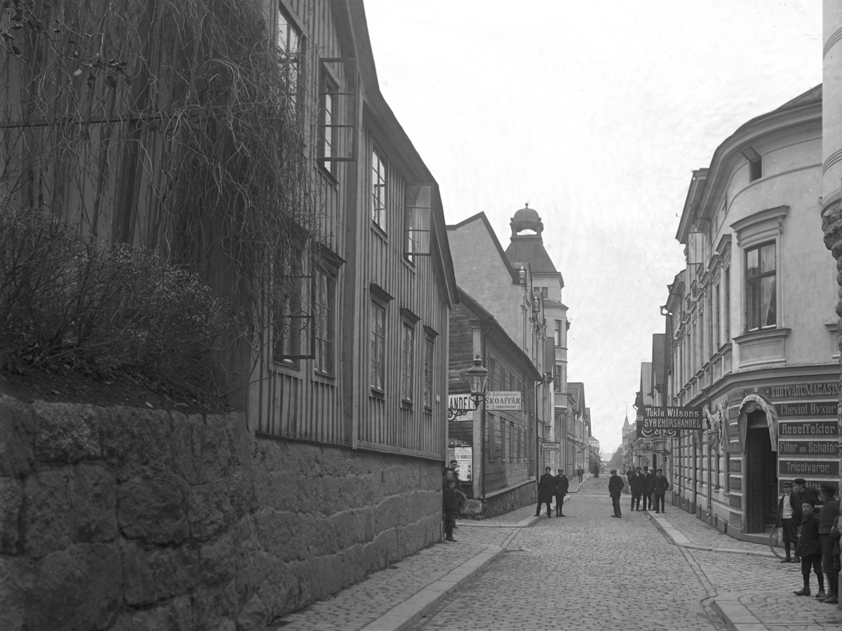 Orig. text: Klostergatan från Tanneforsgatan mot Storgatan.

Till vänster i bild Th. Lifvergrens Skoaffär. Till höger i bild Tekla Wilsons Sybehörshandel.