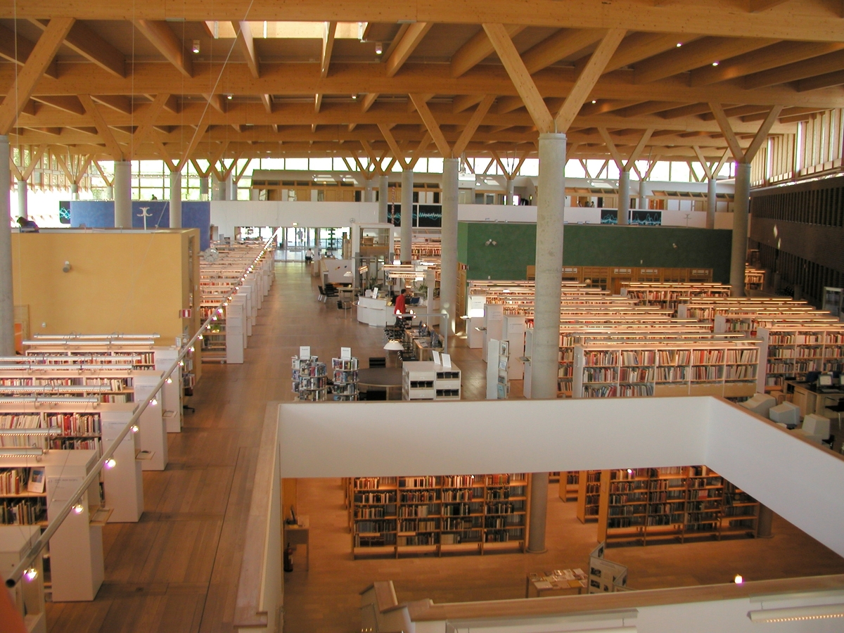 Interiör av Stifts- och landsbiblioteket, bokhallen sedd mot entrén. 
Arkitekten Johan Nyrén ritade förslaget Vända sida och invigningen var 2000-03-16. Byggnadens rena naturmaterial speglar ett ekologiskt tänkande. Under Arkitekturåret 2001 valdes biblioteket till Linköpings mest populära moderna byggnad.