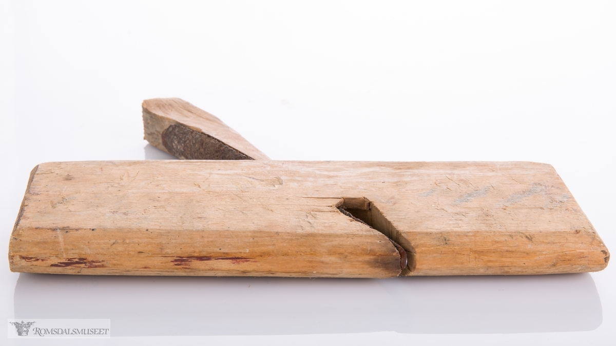Enkel høvel skåret ut av et stykke tre som er avrundet under. Langt avrundet jern og utskåret kile.
