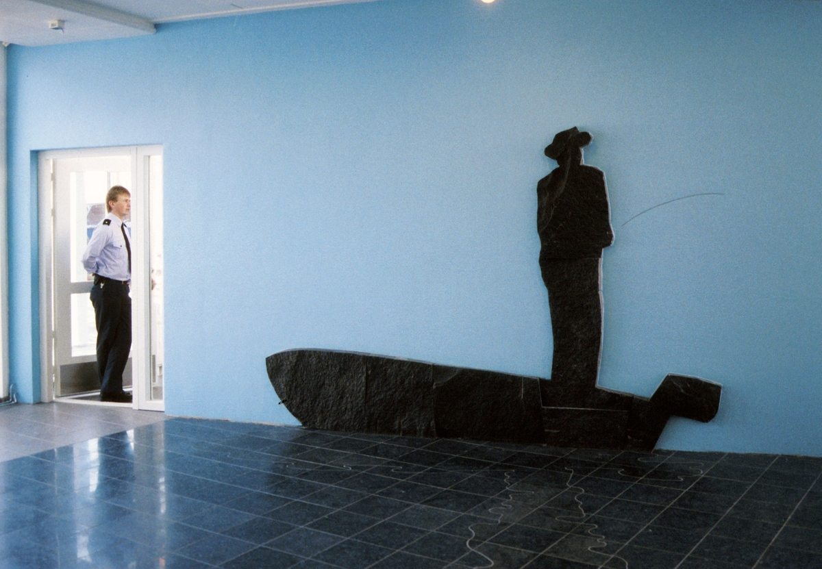Verket er en stilisert tolkning av en figur som står i en båt og fisker med stang. Gulvfeltet foran er dekket med fliser i slipt mørkegrå stein, med et speilbilde av mannen i båten utført i intarsia med en blåaktig polert stein.
