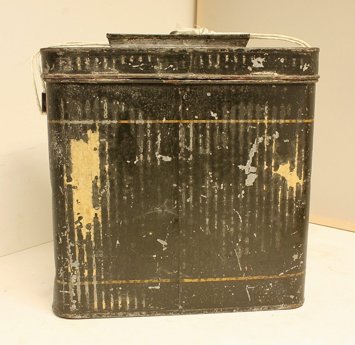 Avrundet, rektangulær boks. Den norske løve på fronten. Rester etter rødt segl. Hvit snor i plast.