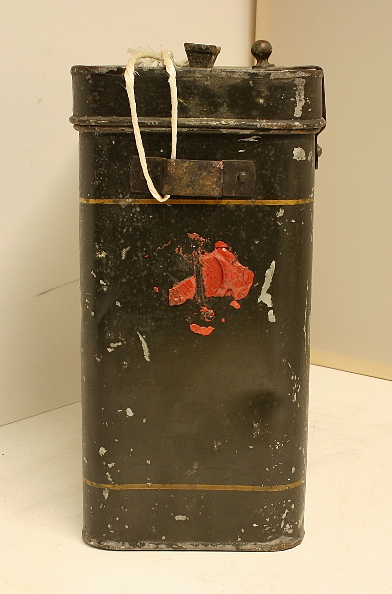 Avrundet, rektangulær boks. Den norske løve på fronten. Rester etter rødt segl. Hvit snor i plast.