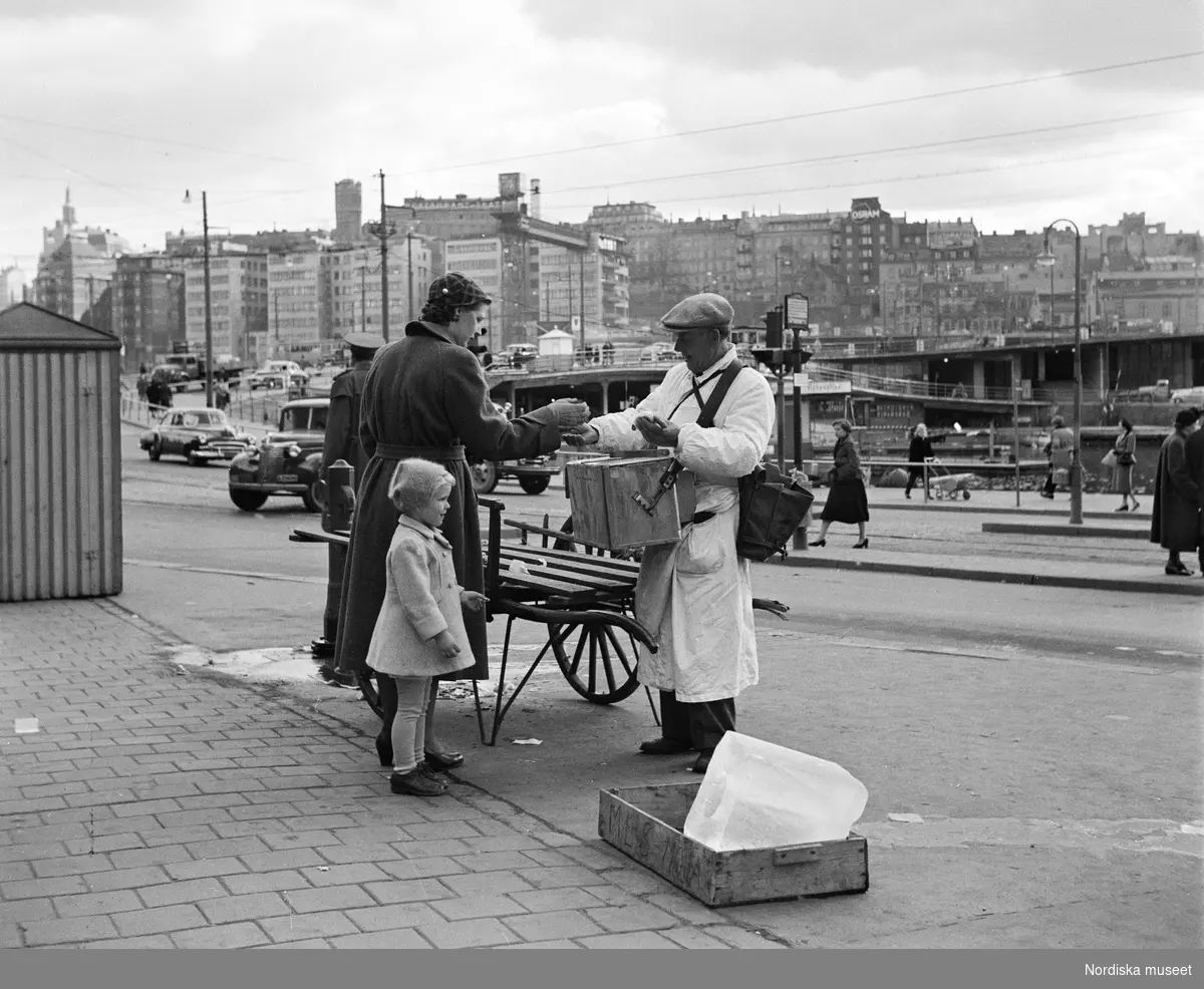 Kvinna och liten flicka köper korv av korvgubbe i Gamla stan.