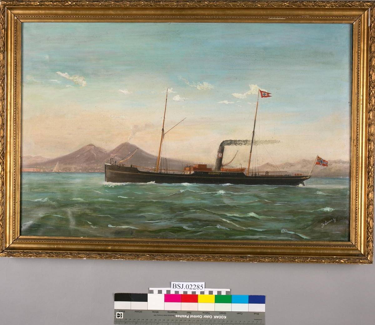 Skipsportrett av dampskipet HERMOD under fart uten seilføring. Trolig utenfor Napoli med vulkanen Vesau i bakgrunnen. Unionsflagg akter.
