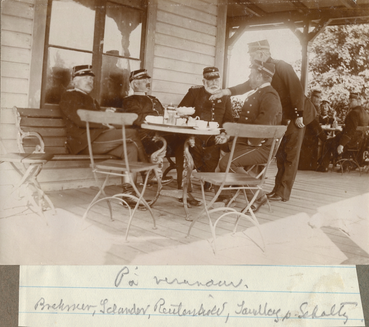Fem officerare från Hälsinge regemente samlade kring kaffebord på verandan. Från vänster major Brehmer, major Selander, överstelöjtnant Reuterskiöld, bataljonsläkare Sandberg och kapten von Schoultz.