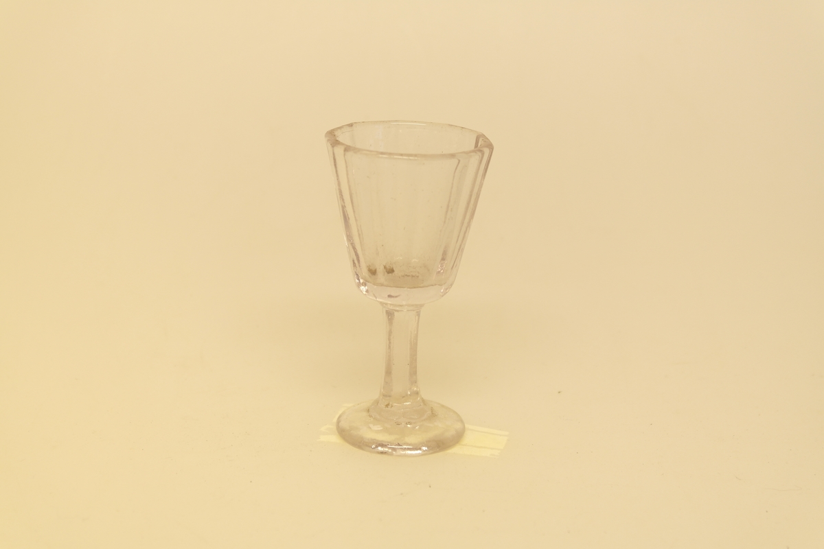 Kryddersett bestående av stativ (a), to flasker (b, c, f) og to glass (d-e).
A) Krydderstativ av tre og støpt messing. Messingkant rundt 4 sirkelåpninger. Fire balusterformede messingbein.
B) Flaske i støpt glass med glasspropp (F)
C) Flaske i støpt glass
D) Støpt glass