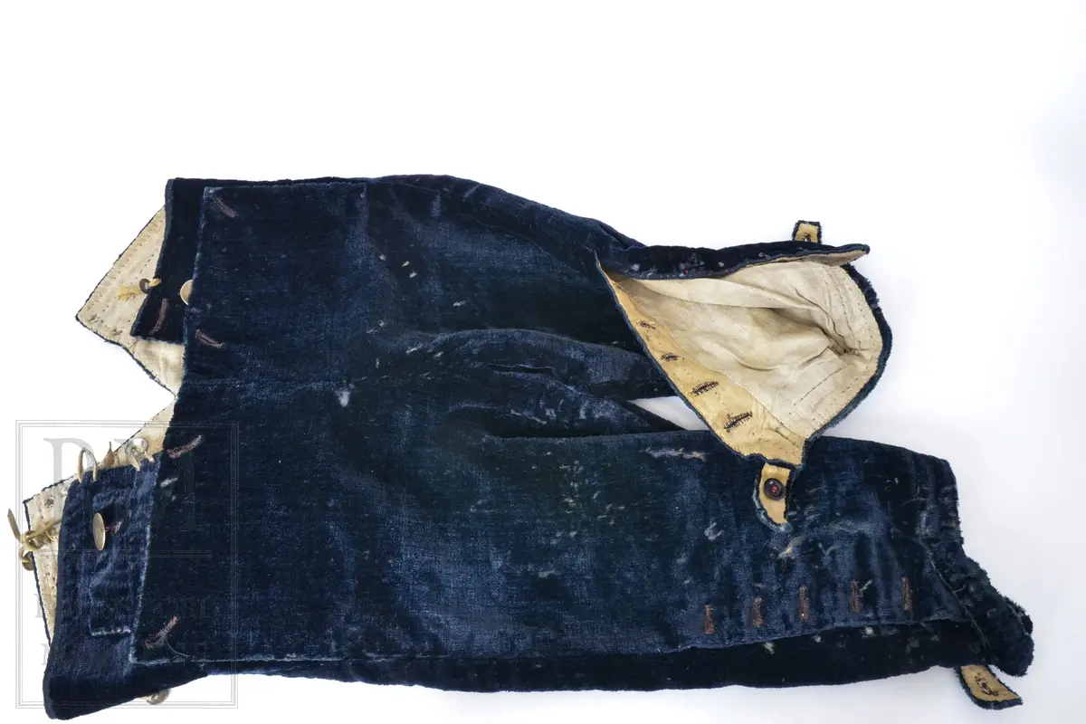 Mørk blå fløyelsbukse, knelang, med lem. Foret i lin. Fem flate messingknapper.