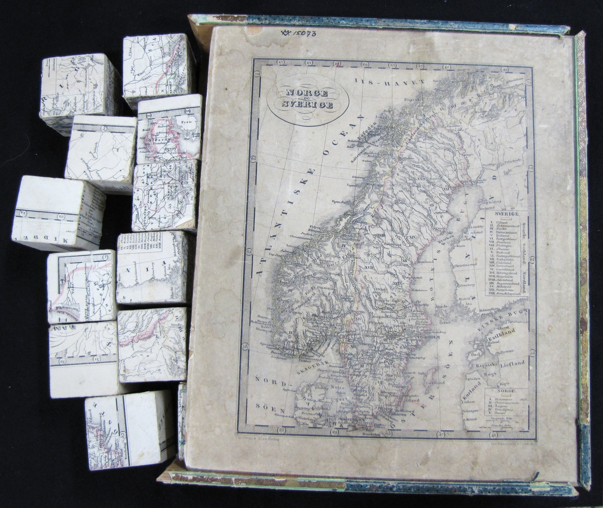 Spel som består av klossar, 42 mm i kvadrat, 30 st, med kartblad. Kartan är över Norge och Sverige.