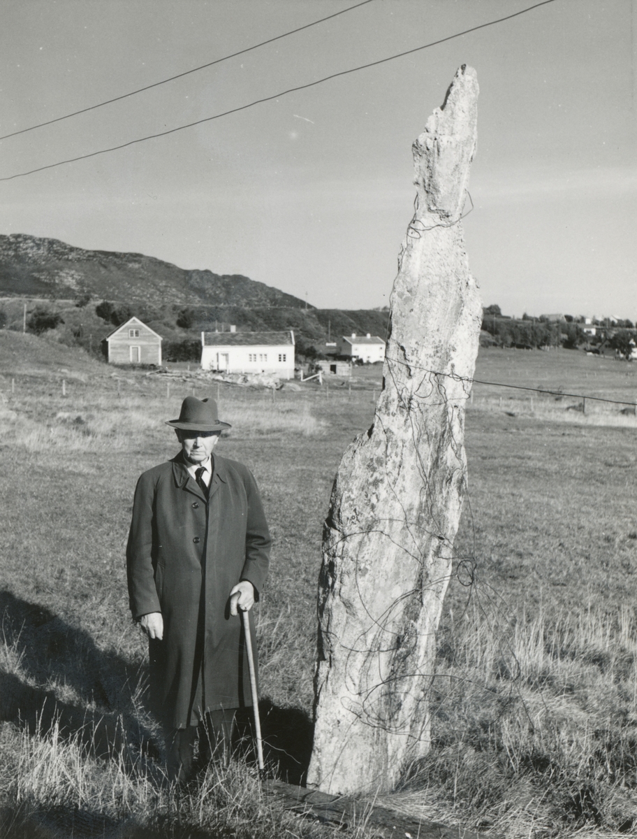 Hans Ratvik står ved ein bautastein på Godøya.