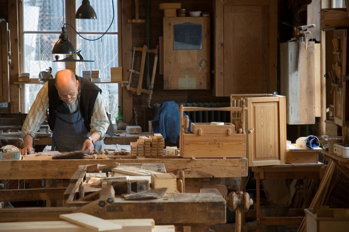 Interiör från Skansens snickerifabrik. Möbelsnickaren arbetar vid sin snickarbänk.