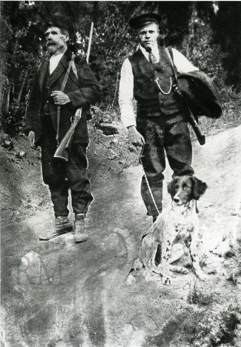 To menn med hund på fuglejakt. Til venstre Anders Bekkelund. Hans Bekkeli eller Olaf Bekkeli med hunden Bella.