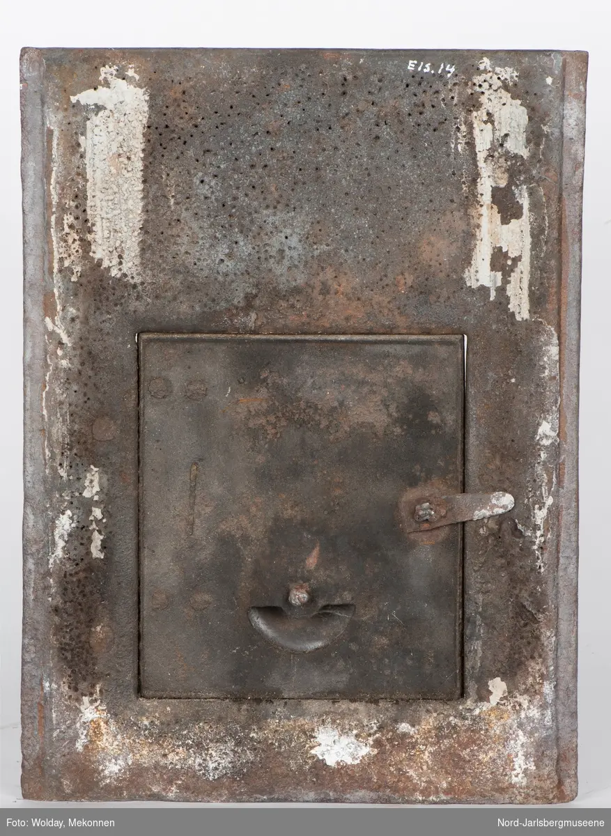 Platen har firedelt rokailleornament i flatrelieff over dør, som ovn reg.nr. EIS.0013. Ikke originaldør sammenlignet med katalogmodellen.