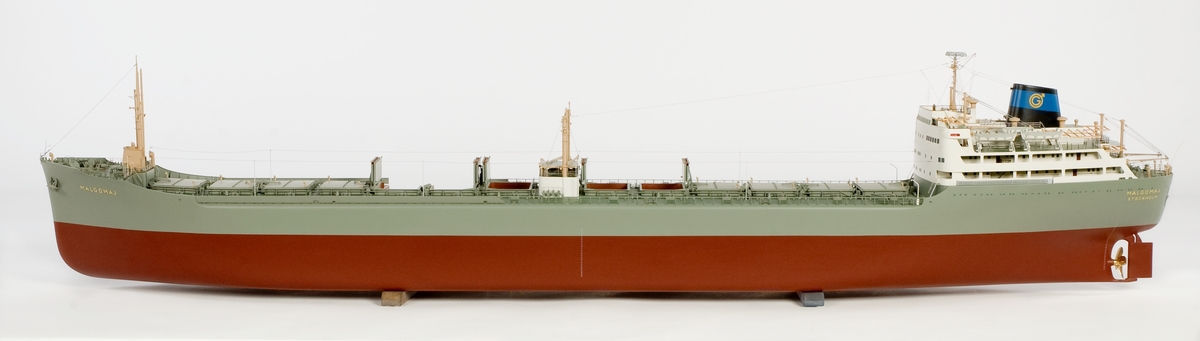 Fartygsmodell av malmtankfartyget MALGOMAJ av Stockholm (b. 1959 i Göteborg, SE 1960) byggd av trä och metall, fullt utrustad, sektion för om bryggan på styrbordssidan öppnad visande malmrum och oljetankar. Två malmrurm som centerlastrum. 13 tvådelade malmlastluckor. 13 tankar på var sida. Brygga och navigationshytt akter. Röd bottenfärg i två kulörer, grå sida, grönt däck, vita överbyggnader. Grängesbergsbolagets märke på skorstenen. Längd = 199,0 cm. St.br. 26,3 cm. Skala l/lOO. Gåva: AB Götaverken, Göteborg l6/l 1962. Litteratur: Svensk Sjöfarts Tidning 1959: sidi 269 (sjös.), 1227 (lev.), 1515 (hav.), 2286 (sjöförkl.)
Anm: Modellen byggd hos AB Sverre, Göteborg.Föremålets form: Helmodell