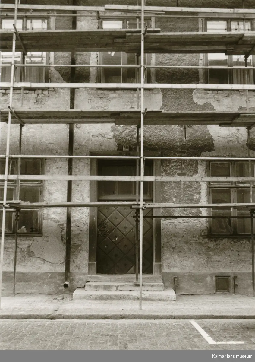 Byggnadsställning framför en putsad fasad.