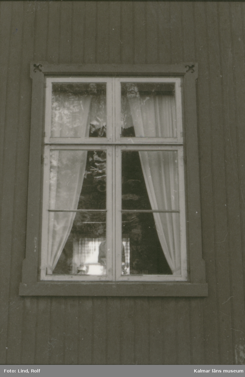 Ett fönster med spröjs i en träfasad.