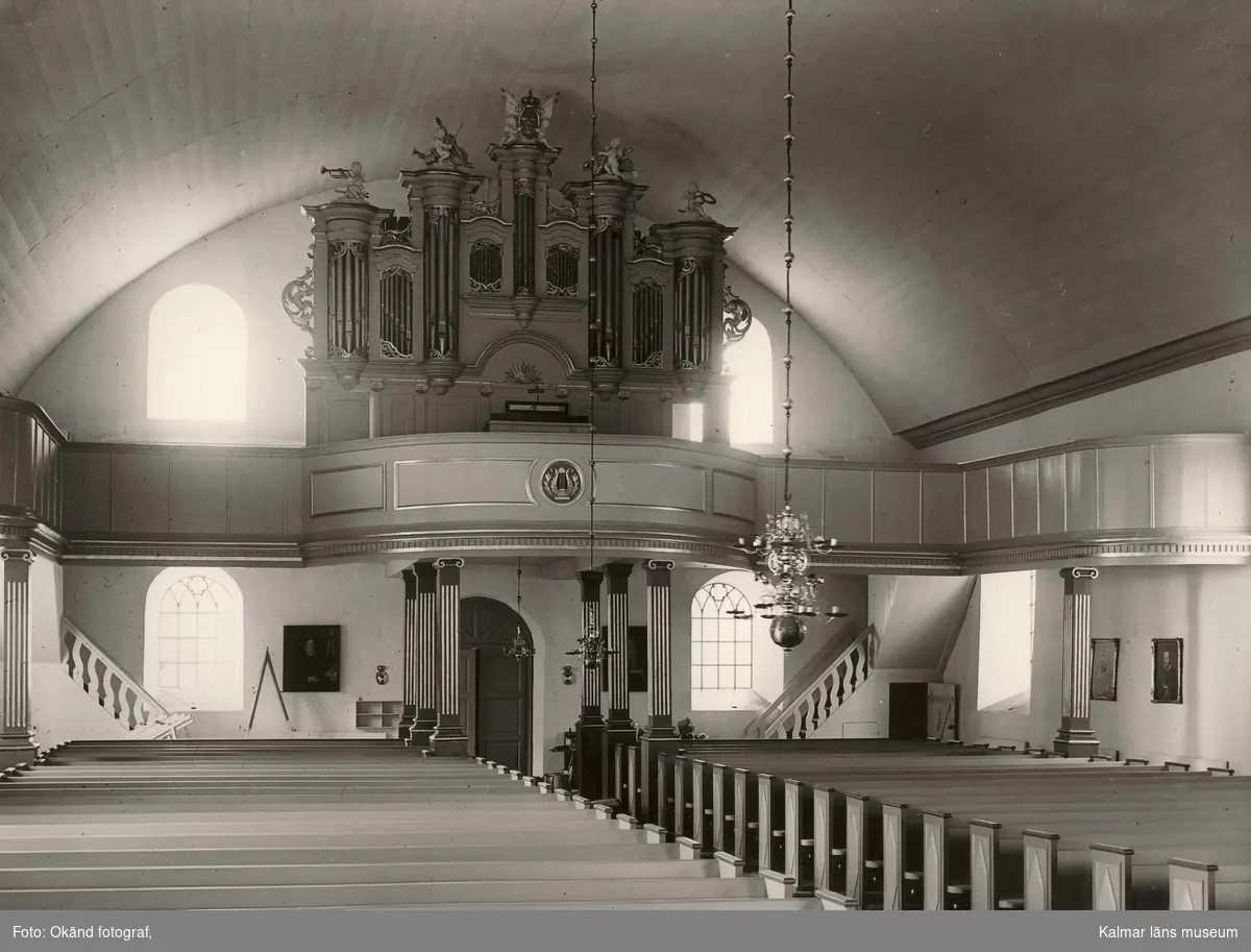 Interiör från Odensvi kyrka med orgel, bänkrader och ljuskronor.