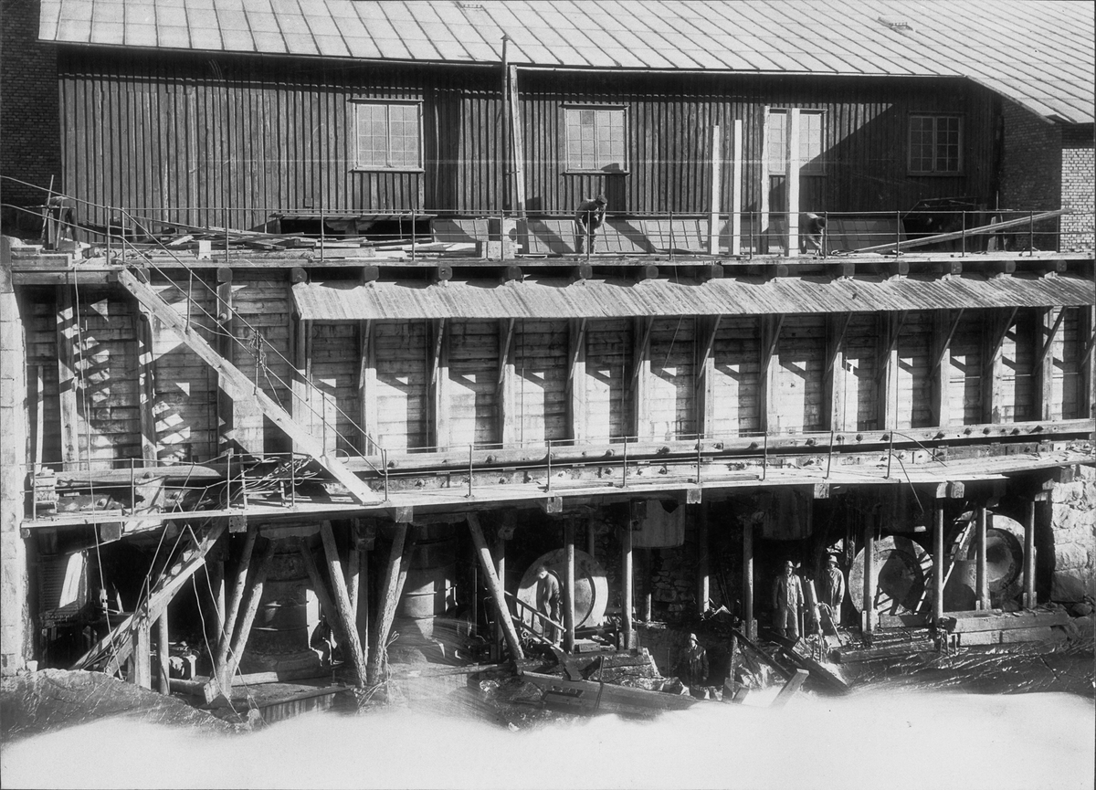 Exteriör av fabriken i Trollhättan (troligen Trollhättans carbid-fabrik). Trollhätte kanal med flera arbetare.