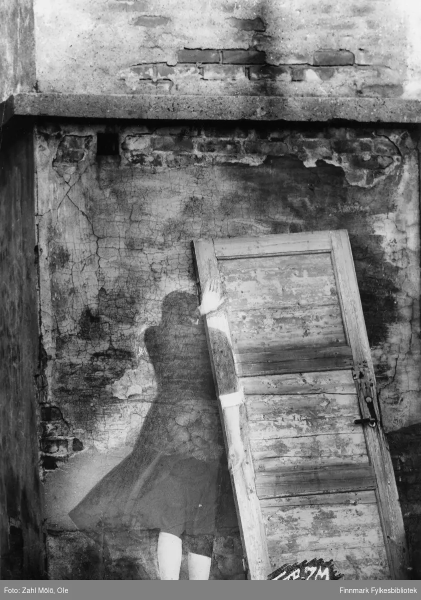 Fotoserie av fotograf Ole Zahl Mölö.  "Spøkelse i Vadsø". Ole Zahl Mölö, også kjent som Zahl Møller under hans tid i Vadsø – med kunstnernavnet OZAM – er født 8.juli i 1937, i Vadsø. Fotoarkivet har ca. 7500 negativer av Ole Zahl Mölös arbeider i sin samling. Bildematerialet inneholder motiv fra Vadsøs lokalmiljø og gjenspeiler hans hverdagsliv i byen og bymiljøet i vekst på 1960-70-tallet.