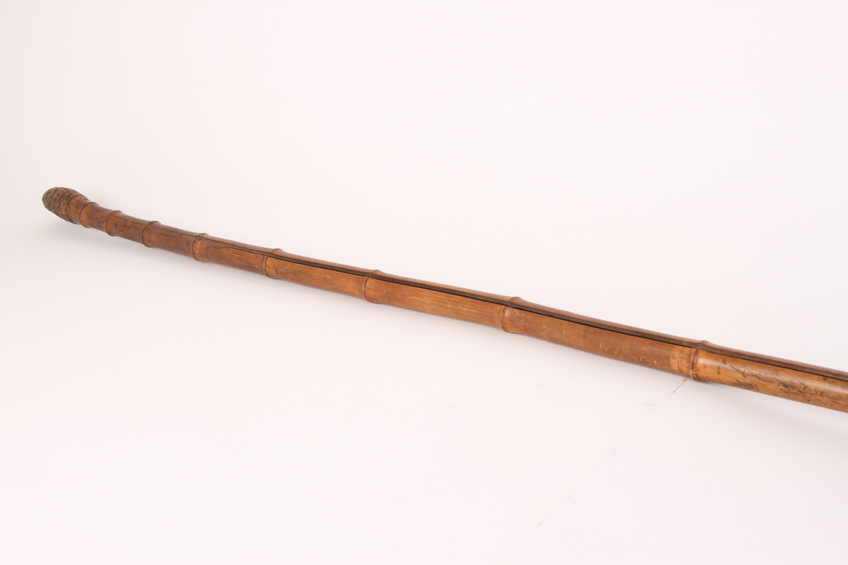 En skistav i bambus med trinse av elghorn og stor jernpigg. Toppen av staven er avrundet, sannsynligvis formet av roten til bambusstaven.