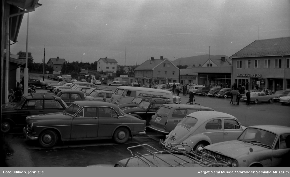 Bossekop i Alta. Alta Samvirkelag til høyre i bildet. Svært mange biler står parkert, muligens i forbindelse med et arrangement.  Alta, Juli 1967