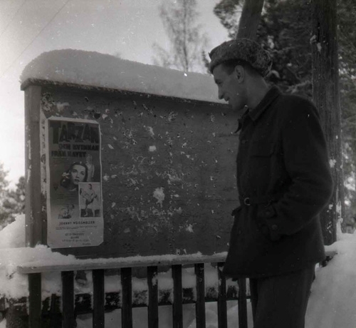 Vid en snöig anslagstavla längs vägen mot Hudiksvall har en man stannat till och läser intresserat den uppsatta affischen. Året är 1950 och det som annonseras är en visning av "Tarzan och  kvinnan från havet". Mannen, med händerna i fickorna och pälsmössa på huvudet, ler när han ser på affischen.