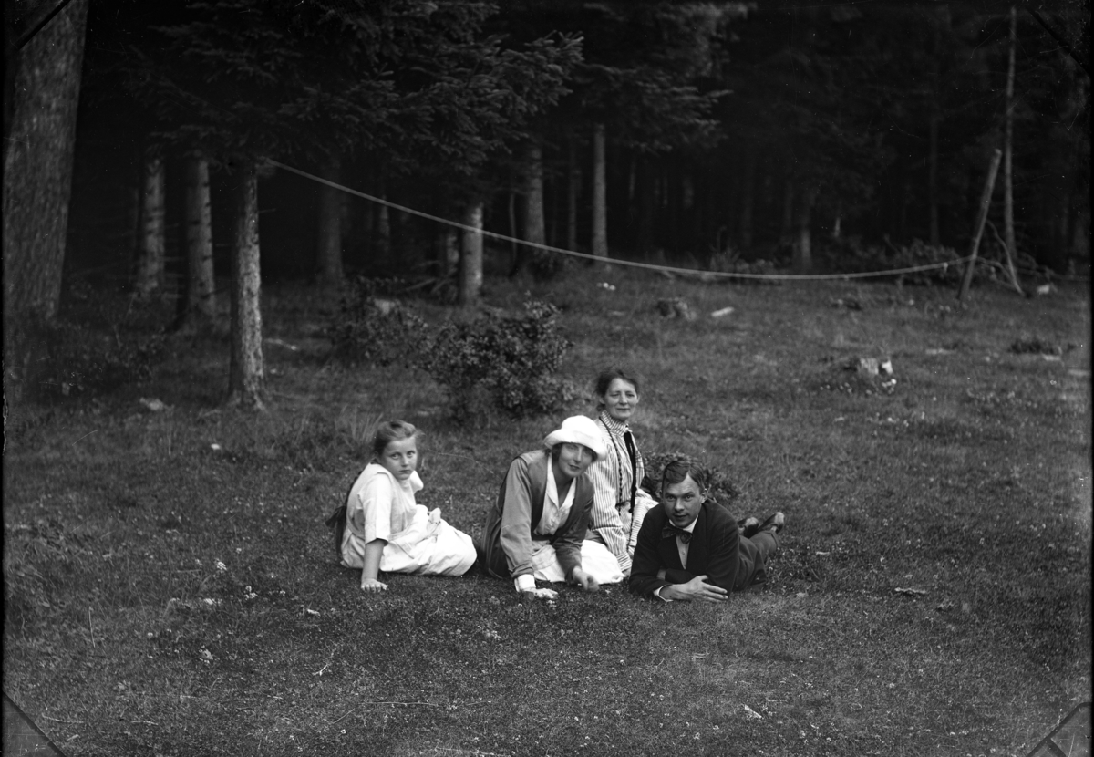 En flicka, två kvinnor och en man sitter respektive ligger i gräset. De är från vänster Birgit, hennes farmor Berta, faster Karin samt Gustaf Bolling.