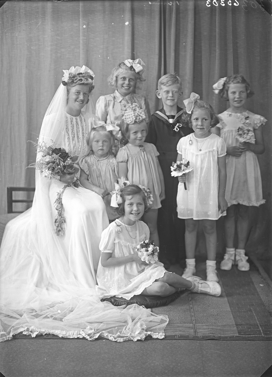 Gruppebilde. Brud med seks unge piker og en ung gutt. Bestillt av Fredrik Jansen. Trygdekassen.