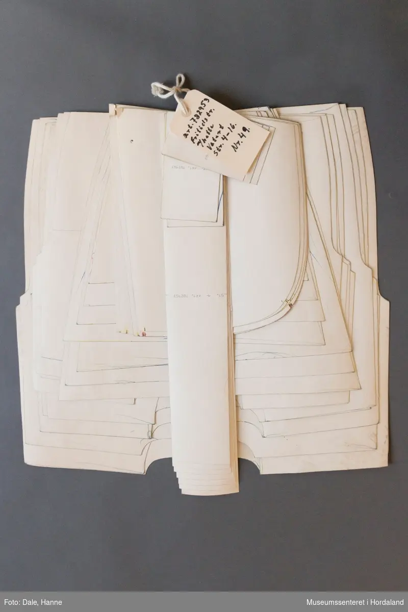 Mønsterskante i papp, brukt til å skjere ut ulike delar av plagg i klesproduksjon. Desse er til fritidstrøyer med hetter, vatterte, str. 4-16 år. Art. nr. 782953, nr. 49.