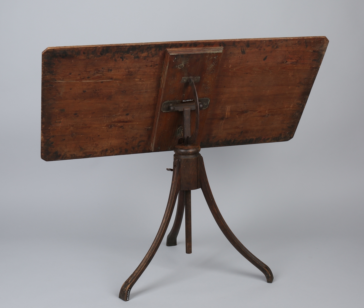 Tegnebord som har tilhørt Ananias Dekke. I tre med sokkelstativ i jern og tre med 3 stk. føtter. Kan reguleres i høyden.