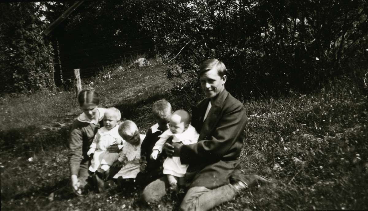 Mann, Erik Källström, med hustru og fire små barn. Sittende i skråning ved Herrmundsbruket, Dalarne.