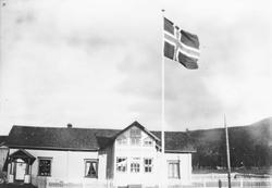 Bolighus, flaggstang m/flagg, gjerde.