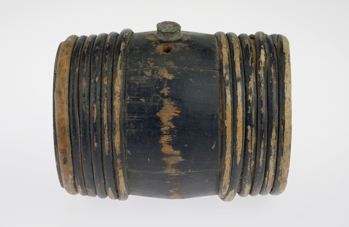 Av gran, lagget, malt svart, med 6 vidjebånd på hver ende. Tut og skrukork av bly på soden, og et mindre hull ved siden av tuten.  Innskåret på ene bunnen: "EV".