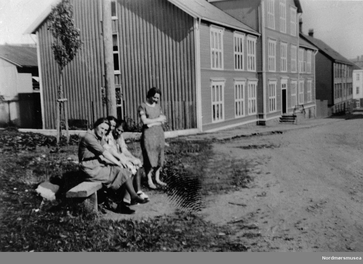 Dette er i Konsul Knudtzons gate og det er det gamle sjømannshjemmet man ser midt på her. Få meter bak ryggen til fotografen ligger det gamle sykehuset. (Info: Tor Aage Dyrseth Zdrinka).  4 jenter på en benk.  Kristiansund 1920-30? Nordmøre museums fotosamling
