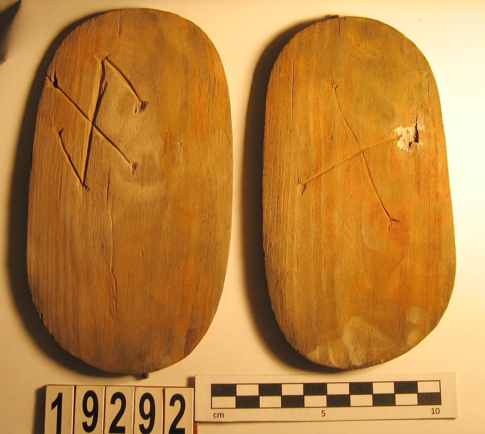 En svepask, i delar. Delarna utgörs av ett lock, en botten samt fragment av svepet. Locket och botten är båda försedda med varsitt bomärke.