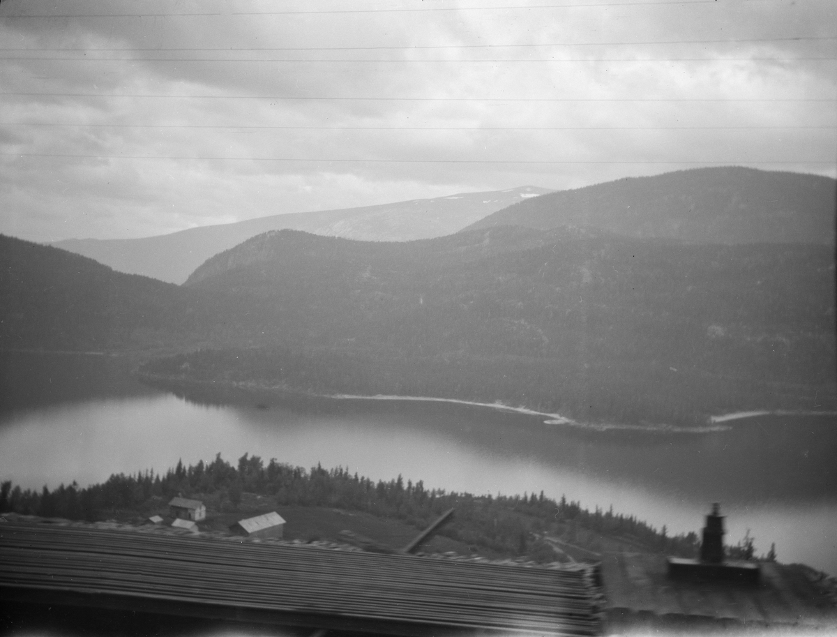 Utsikt over en innsjø i skogområde, antagelig tatt fra tog vindu, kan være Hallingdal, Krøderen