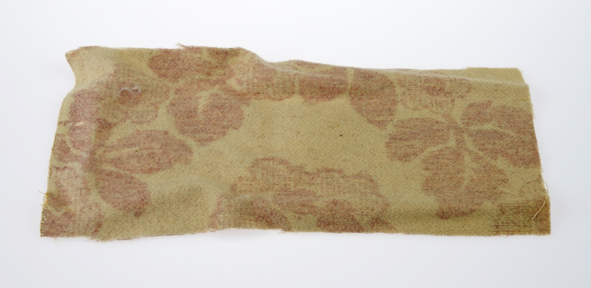 En sjokoladeeske brukt som dukkeseng med dukke, dyne, pute, skinnfell, ullteppe og madrass. Gjenstandene er undernummerert 01-08.
FTT.54432.01: En sjokoladeeske fra Freia brukt som dukkeseng. Esken er med lokk og laget av papp. Den er stiftet i hjørnene. Utenpå er det trykt julenissehoder i rødt og grønt. For tekst se "Påført tekst/merker".
FTT.54432.02: En dukke laget av plast der både armer og bein er bevegelige ved at de er festet med strikk inni dukken. Håret er støpt og er krøllet ved ørene. I ansiktet er det malt øyebryn, øyne, røde kinn og munn. Dukken har på seg en pyjamas laget av flanell. Den er stripete i fargene hvit, blå, lys oransje og grønn. På skjorten er det to knapper i fronten.
FTT.54432.03: En hodepute laget av blått bomullsstoff med heklet trekk. Puten er fyllt med diverse tekstilbiter.
FTT.54432.04: En dyne laget av blått bomullsstoff med en påsydd blondekant foran. Baksiden er sydd sammen av tre ulike tekstiler. Dynen er fyllt med tekstilbiter.
FTT.54432.05: En brunsvart skinnfell, trolig laget av kaninpels.
FTT.54432.06: Et ullteppe som trolig klippet ut av et eksisterende ullteppe. Teppet er gulhvitt med blomster og blader i rosalilla.
FTT.54432.07: Et sammenbrettet stykke som er heklet. Trolig en rest som er brukt som madrass i esken/sengen.
FTT.54432.08: Et sammenbrettet stykke som er heklet. Trolig en rest som er brukt som madrass i esken/sengen.