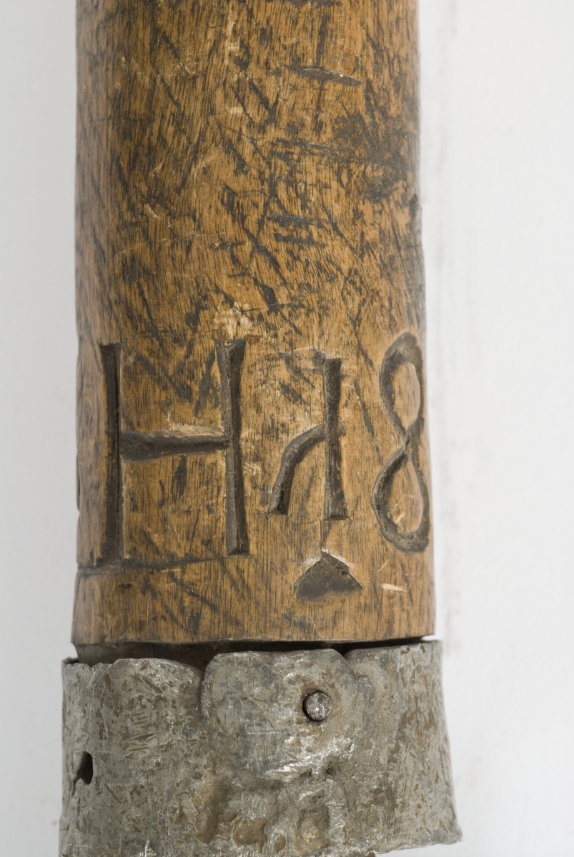 Tregrep med hvitt metall ring nederst. Knappen er formet i treverk..Grepet har innskåret intialer PISH 1824.
Rett tveegget klinge med elipseformet tverrsnitt. To midtstillt smale blodrender.Dekor for enden av blodrendene på begge sider.
