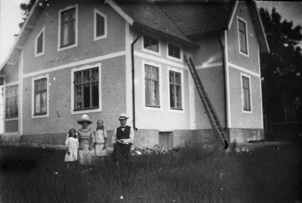 Två vuxna och två barn framför ett bostadshus.