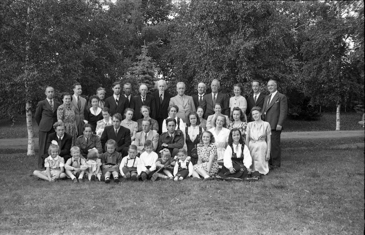 En gruppe personer, trolig i hagen på gården Lunna i Østre Toten. Muligens familieportrett, men ingen av personene er identifisert.