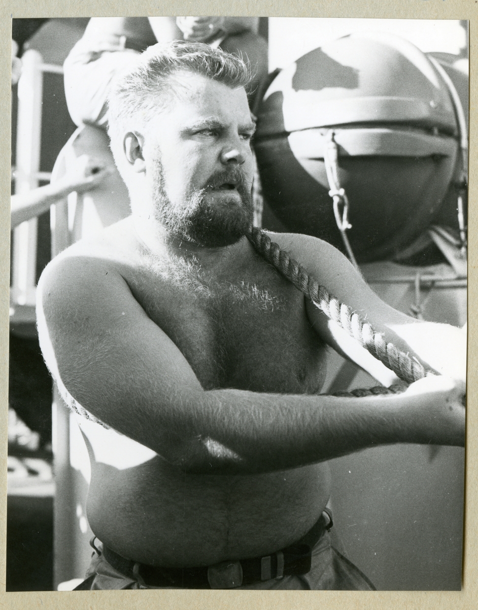 Bilden föreställer en besättningsman i fysiskt arbete ombord på minfartyget Älvsnabben under långresan 1966-1967.
