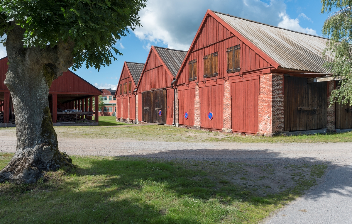 Fotodokumentation av byggnader på Lindholmen i Karlskrona. Till höger: Skjul för förvaring av ekvirke. Skjul 13, 14, 15. Dessa ritades av överstelöjtnant-mekanikus Jonas Lindströmer. Byggnaderna uppfördes omkring sekelskiftet 1800. Tll vänster: Slitaget byggdes omkring 1850 användes som ett virkesskjul. De runda träpelare ska ha varit utrangerade mastträn. Byggnaden är ca: 96 meter.