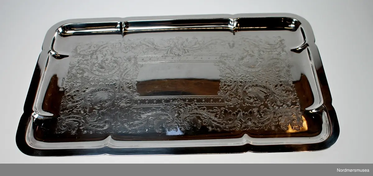 Fløtesett som består av et brett, en sukkerkopp og en fløtemugge i sølvplett. Brettet har innrisset dekor i bunnen. Sukkerkopp og fløtemugge har 4 føttet og hank. Dekor over hver fot og øverst på hanken. En løs papirlapp med påskrift "Raufoss 1952 1. premie 17 km " ligger på brettet.