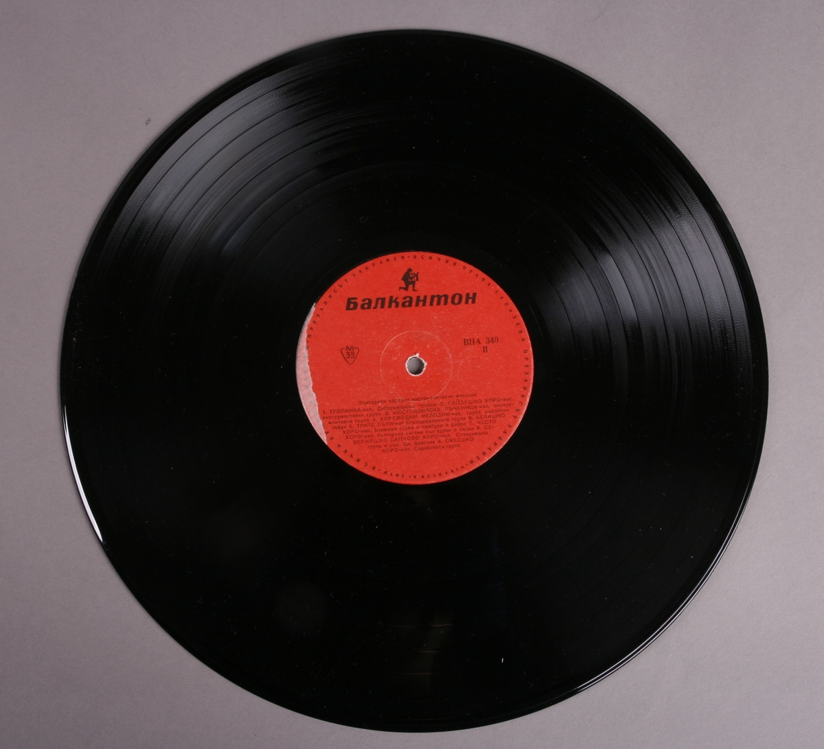 Grammofonplate i svart vinyl med plateomslag av papir. Platen ligger i en Plastlomme. Påskrift med blyant på baksiden av plateomslaget (se bilde).