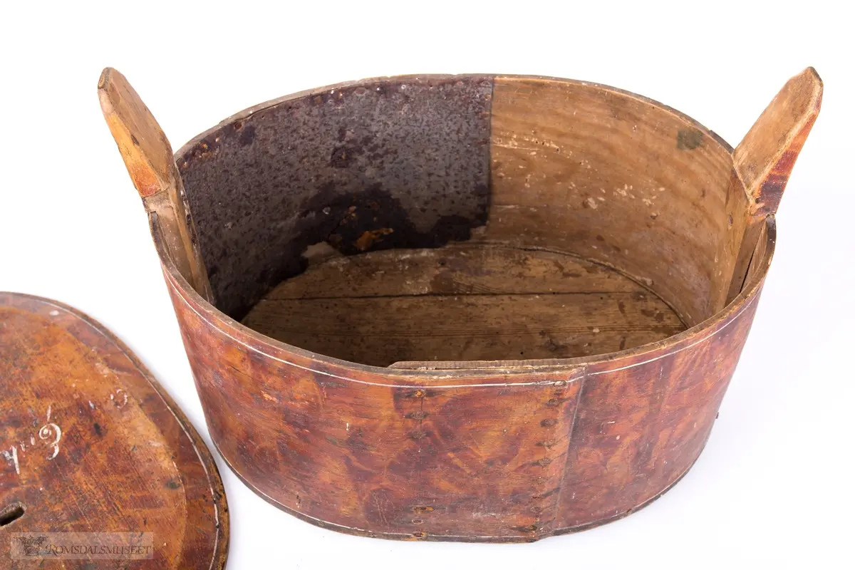 Hvite linjer langs kanten. Avrundet lokk. Innskrift.