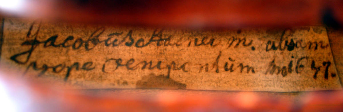 Fiolinkasse (a), folin (b) og bue (c). Kassen er i lær. Åpning i begge ender. Hemmelig rom i toppen. Preget dekor i læret. Kassa har lås. Fiolinen er god, kassen er slitt