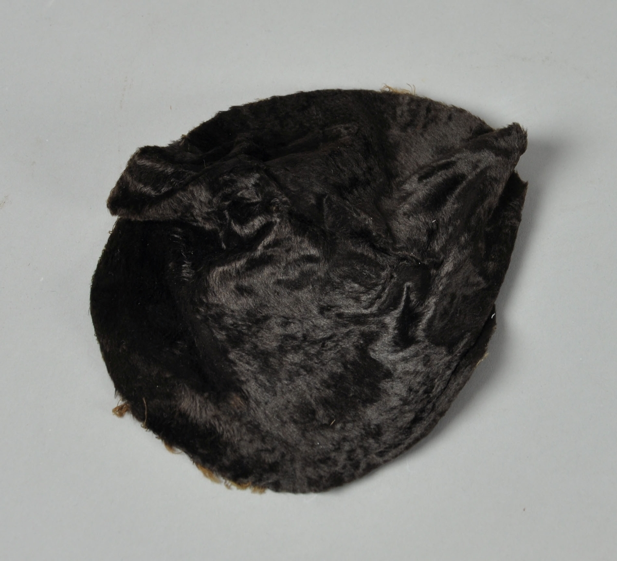 Rundt utsnitt av svart skinn / pels til flosshatt. Utsnittet er til toppen av pullen.