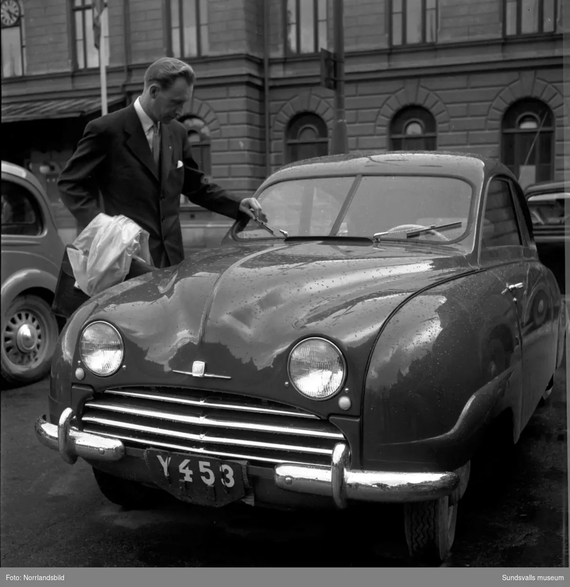 En man bredvid en Saab med registreringsnummer Y453 utanför Stadshuset.