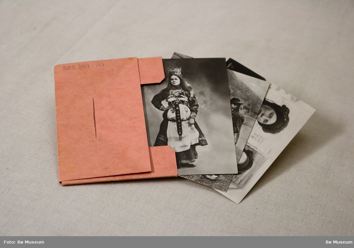 Lita mappe/konvolutt med 10 fotografi som syner modellar i norske folkedrakter. Framsida har eit stempla frimerke til 20 øre. Baksida syner logoen til firmaet Mittet & Co.