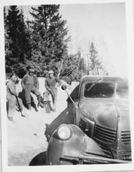 Tre arbeidere med spader stående ved en lastebil. Laster gjø