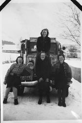 Fire jenter står oppstilt foran en lastebil.